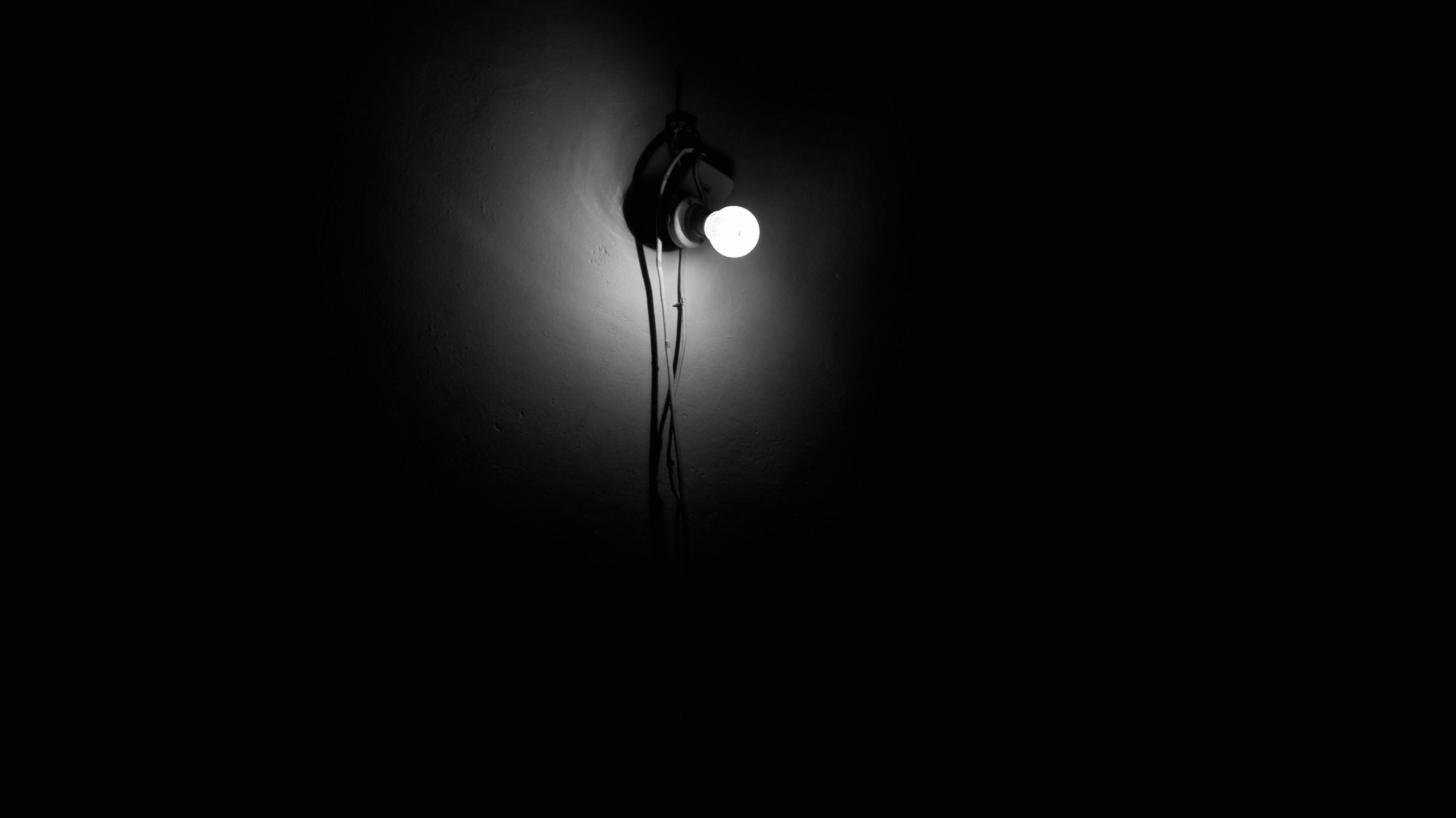A bare light bulb illuminating a dark room